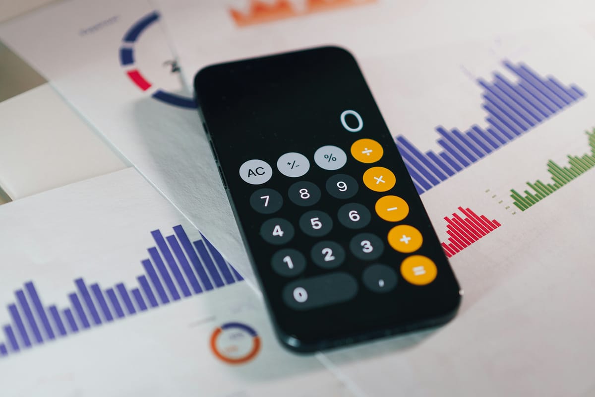 A phone calculator lying on printed bar charts and donut charts